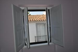 een open raam met uitzicht op een dak bij A Casa do Mestre in Évora