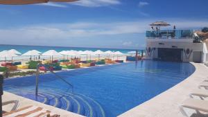 a swimming pool with chairs and the ocean in the background at Cozy and Modern in Cancún