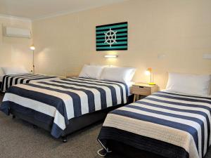 a hotel room with two beds and two nightstands at Sail Inn Motel in Yeppoon