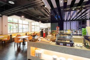 a restaurant with a counter and tables and chairs at Holiday Garden Hotel SKM Park in Kaohsiung