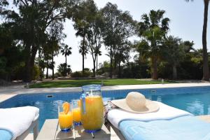two glasses of orange juice on a table next to a swimming pool at Deluxe First Line Villa in Perivolia