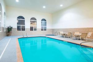 Oacoma的住宿－Howard Johnson by Wyndham Oacoma Hotel & Suites，大楼内一个带椅子和桌子的游泳池