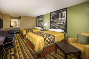a hotel room with two beds and a couch at Super 8 by Wyndham Paragould in Paragould