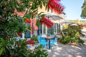 a table and chairs in front of a building with red flowers at Tenuta Valdelmelo in Castiglione della Pescaia