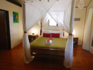 a bedroom with a canopy bed with red pillows at Maqai Beach Eco Resort in Qamea