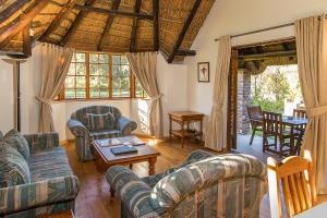 a living room with couches and a table at Coral Tree Cottages in Harkerville