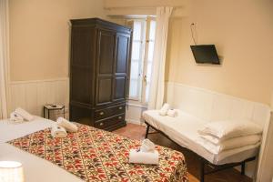 a room with two beds and a cabinet and a tv at Hostal Callejon del Agua in Seville