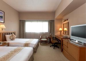 Habitación de hotel con 2 camas y escritorio con TV. en First Hotel, en Taipéi