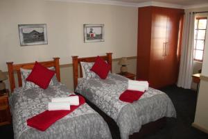 1 dormitorio con 2 camas y almohadas rojas y blancas en Victoria Heights B&B, en George