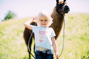 a young girl walking a camel in a field at Pitzis Kinderhotel - Family Only in Arzl im Pitztal