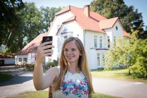 uma mulher tirando uma foto de uma casa em Komfort-Ferienwohnungen"Am Furlbach" em Schloß Holte-Stukenbrock