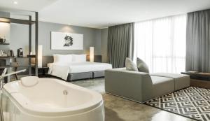 une chambre d'hôtel avec une baignoire et un lit dans l'établissement Zazz Urban Bangkok, à Bangkok
