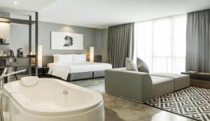 una habitación de hotel con bañera y cama en ZAZZ Urban Bangkok, en Bangkok