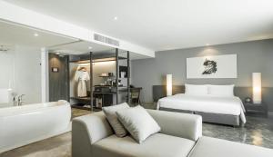1 dormitorio con cama, bañera y sofá en ZAZZ Urban Bangkok, en Bangkok