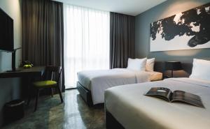 a hotel room with two beds and a desk at Zazz Urban Bangkok in Bangkok