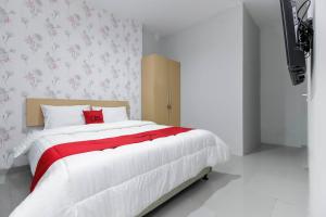 a bedroom with a large white bed with a red blanket at RedDoorz Syariah near Metropolitan Mall Bekasi in Bekasi