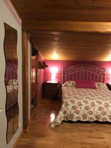 1 dormitorio con 1 cama con pared de color rosa en Les Piperes, en Corao