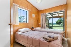 two beds in a room with a window at Pickering Barn Stay in Tamahere