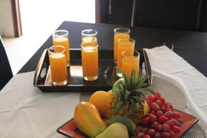 a tray of fruit on a table with glasses of orange juice at Ikaze Guest House in Boksburg