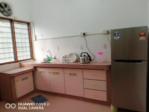 cocina con armarios rosados y nevera en Taiping Guest House en Taiping