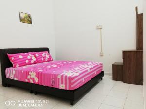 a bedroom with a bed with pink sheets and a pink at Taiping Guest House in Taiping