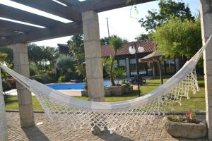 a hammock in front of a house with a pool at Alagoas4Family - Country House in Arouca