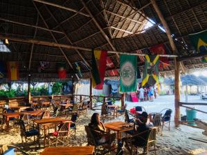 a group of people sitting at tables in a restaurant at Mocco Beach Villa in Kendwa