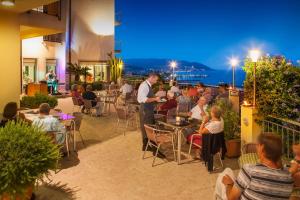 a group of people sitting at tables on a patio at night at Hotel Metropol in Diano Marina