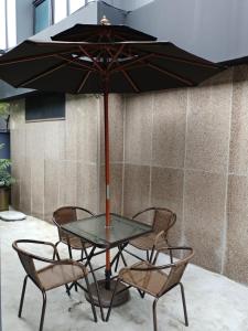 une table en verre avec des chaises et un parasol dans l'établissement Hotel The May, à Busan