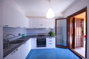 uma cozinha com armários brancos e um piso azul em BIANCA - Il mare a Roma em Palo