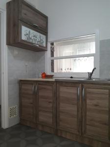 a kitchen with wooden cabinets and a window at Eszterlánc Apartman Eger in Eger