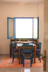 a dining room table with blue chairs and a window at Τhe White Houses in Makry Gialos