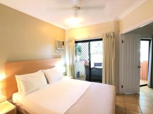 1 dormitorio con cama blanca y balcón en City Plaza Apartments, en Cairns