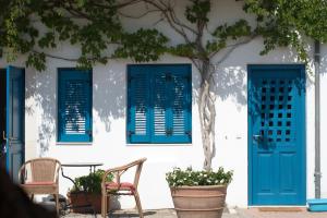 a building with blue shutters and a table and chairs at Τhe White Houses in Makry Gialos