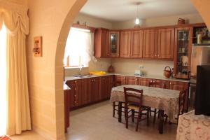 a kitchen with wooden cabinets and a table with chairs at Grazzja Traditional Apartment in Żabbar