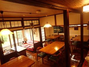 une salle à manger avec des tables et des chaises en bois dans l'établissement Yufuin Country Road Youth Hostel, à Yufu