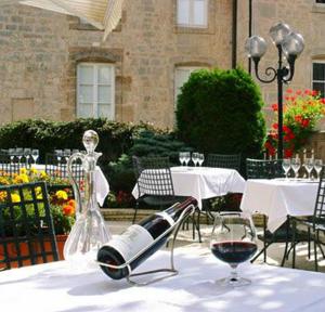 uma mesa com uma garrafa de vinho e um copo em Logis Hôtel Le Cheval Blanc em Langres