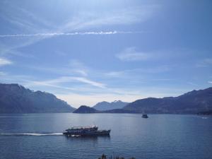 a boat on a lake with mountains in the background at Hotel Du Lac Menaggio in Menaggio