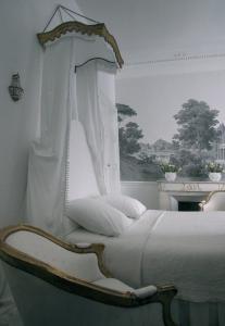 - une chambre avec un lit blanc à baldaquin dans l'établissement L'Hôtel Particulier, à Arles
