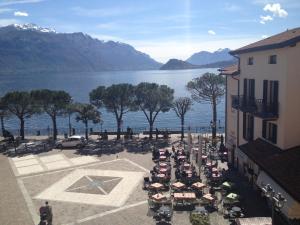 a group of tables and chairs next to a body of water at Hotel Du Lac Menaggio in Menaggio