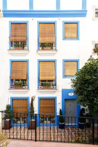 a white building with blue windows with orange blinds at Marbella Old Town House in Marbella