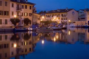 a group of buildings and boats in the water at night at Galleria Excelsior in Grado