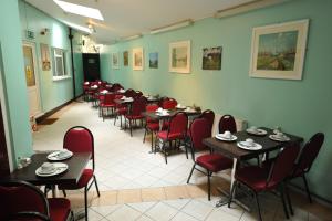 a dining room filled with tables and red chairs at Acton Town Hotel in London