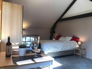 een slaapkamer met een bed en een tafel met wijnflessen bij Gîtes du Golf in Sart-Dames-Avelines