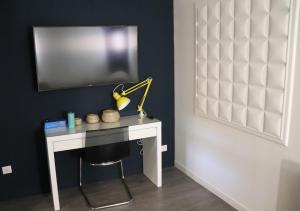 a room with a desk with a tv on a wall at Les pièces du puzzle in Dunkerque