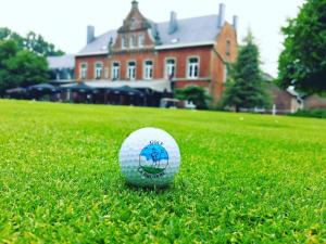 a golf ball sitting in the grass in front of a house at Gîtes du Golf in Sart-Dames-Avelines