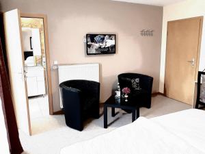 a bedroom with two chairs and a table and a mirror at Hotel Restaurant Denis in Zemmer