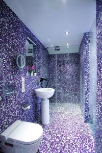 a bathroom with a toilet and a shower with purple tiles at abito Suites in Leipzig