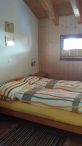 ein Schlafzimmer mit einem Bett mit gestreifter Decke und einem Fenster in der Unterkunft Angela in Münster VS