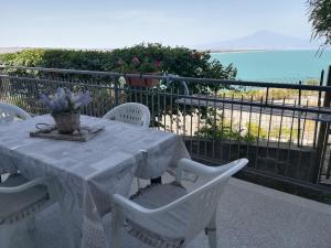 uma mesa branca e cadeiras numa varanda com o oceano em Villa Margiu - Casa Ossino em Agnone Bagni